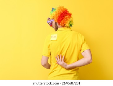 Funny man in disguise and with sticky note on his back against yellow background. April fools' day celebration