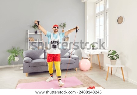 Funny man is exercising at home, using fitness bands for stretching and workout. Dedication to sport and fitness is evident in home training routine, showcasing commitment to staying fit.