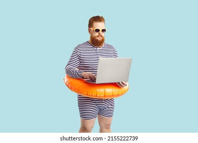 Funny man finds time for business during summer holiday at seaside. Serious chubby entrepreneur working on computer while on vacation. Busy plus size guy in striped swimsuit using his laptop at beach