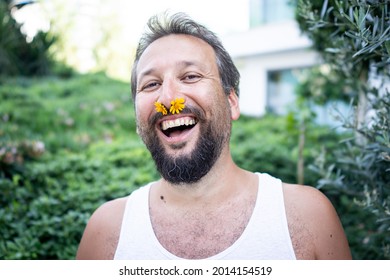 Funny man with flower in nose laughing in garden