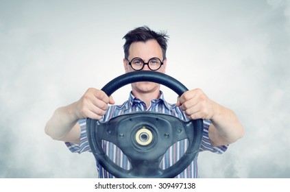 Funny man in glasses with a steering wheel, car drive concept