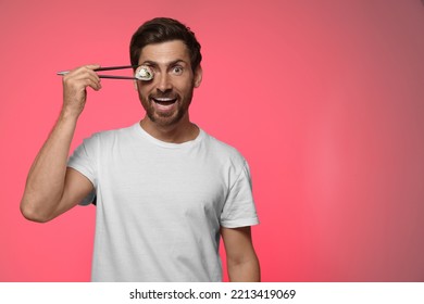 Funny Man Hiding His Eye With Tasty Sushi Roll On Pink Background. Space For Text