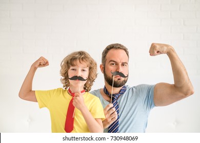 Funny Man And Kid With Fake Mustache. Happy Family Playing In Home. Movember Concept