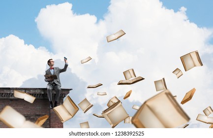 Funny man in red glasses and suit sitting on building top and reading book - Shutterstock ID 1238392525