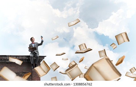 Funny man in red glasses and suit sitting on building top and reading book - Shutterstock ID 1308856762