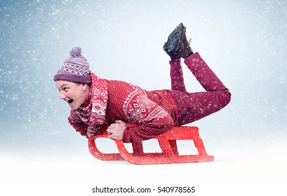 Funny Man In Red Sweater And Cap On Sled In The Snow, Concept Winter Fun