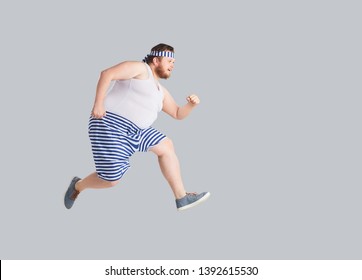 Funny Man In Striped Shorts Runs On A Gray Background.