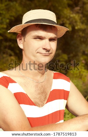 Funny man in stylish retro swimsuit and straw hat swimming in river 