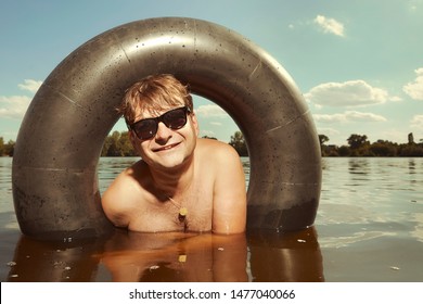 Funny Man In Sunglasses Swimming In Lake On Inner Tube