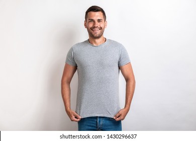 Funny man wearing in grey t-shirt standing pulling down a t-shirt smiling and looking at the camera.- Image - Shutterstock ID 1430296637