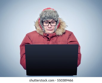 Funny Man In Winter Clothing In Front Of A Laptop. Russian Hacker Concept