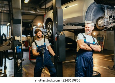 Funny mechanical engineering joking in car repair shop or garage. Workflow in a car workshop. Father working with his son. Family business concept.