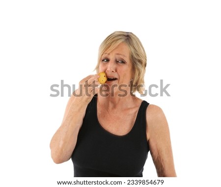 Funny middle aged woman eating a biscuit against a white background