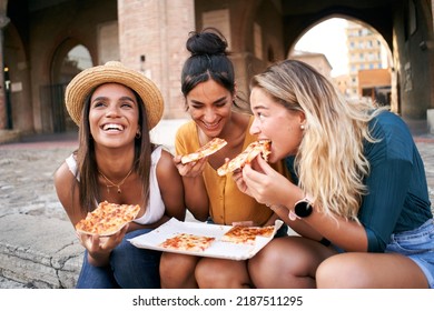 Funny mixed race group of three women eating street food outdoors in the city street. Happy female friends enjoying the summer vacations together European city. Young people lifestyle concept - Powered by Shutterstock