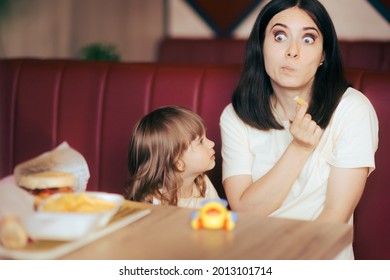 Funny Mom Wearing Clown Nose Celebrating Daughter In A Restaurant. Mother Entertaining Her Toddler Child For Its Birthday Throwing A Party In A Fast Food Diner
