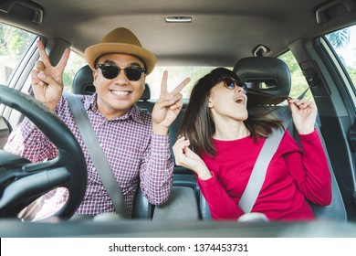 Funny moment couple asian man and woman sitting in car. Enjoying travel concept.