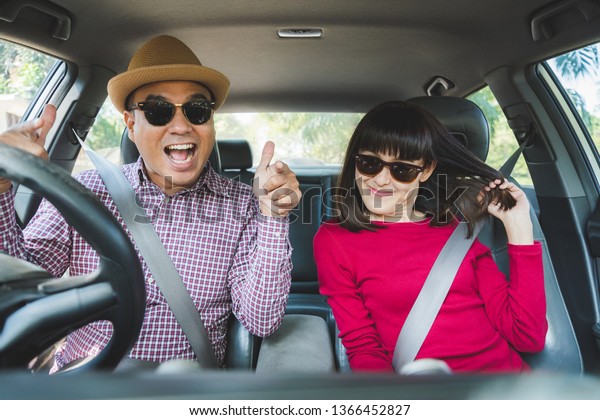 Funny moment couple asian man and woman sitting
in car. Enjoying travel
concept.