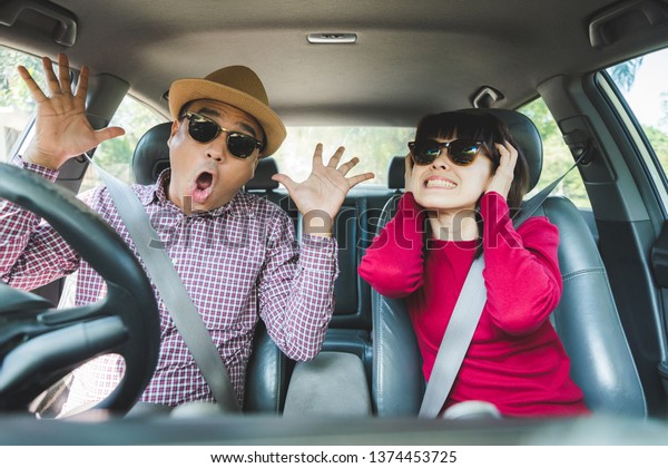Funny moment couple asian man and woman sitting\
in car. Enjoying travel\
concept.