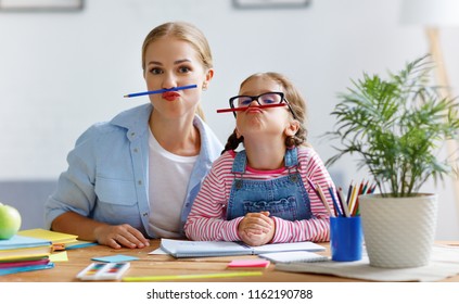 funny mother and child daughter doing homework writing and reading at home