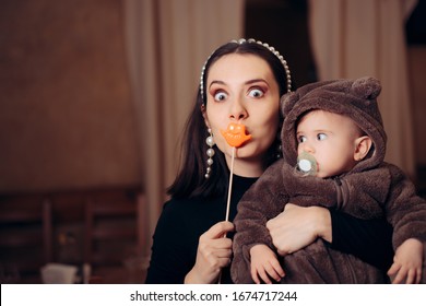Funny Mother with Party Accessory Holding Baby. Silly quirky millennial mom having a sense of humor
