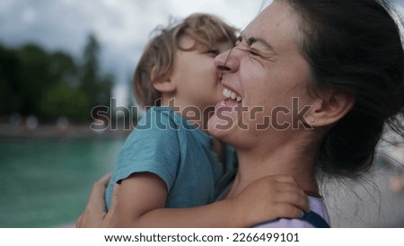 Funny mother and son moment. Little boy kissing mom in cheek pretending to be disgusted. Family lifestyle bonding moment. Authentic real life