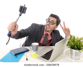 Funny Nerd Businessman With Thick Glasses In Suit And Tie Working At Office Desk Taking Selfie Photo With Mobile Phone Camera And Stick Posing Happy And Successful Isolated On White Background