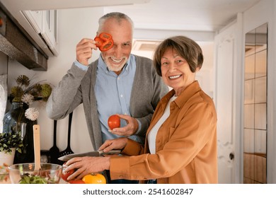 Funny old elderly senior couple spouses cooking, cutting vegetables at home kitchen, preparing food dinner in mini van trailer camper home - Powered by Shutterstock