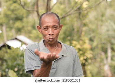 A funny old filipino man blows an imaginary kiss. Pursed lips signifying either a lighthearted gesture or catcalling. Outdoor scene. - Shutterstock ID 2193001331