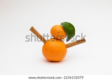 Funny orange and tangerine snowman with cinnamon hands on a white background