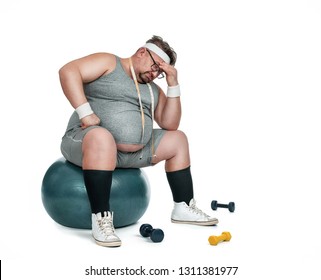 Funny Overweight Sports Man Sitting Depressed On The Fitness Ball Isolated On White Background 