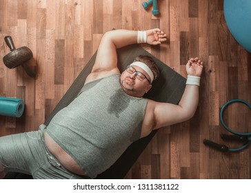 Funny overweight sportsman lying exhausted down on the floor 