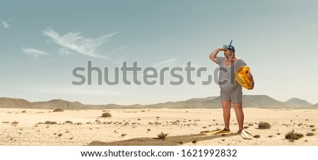 Funny overweight swimmer looking for the beach  in the middle of the desert with copy space