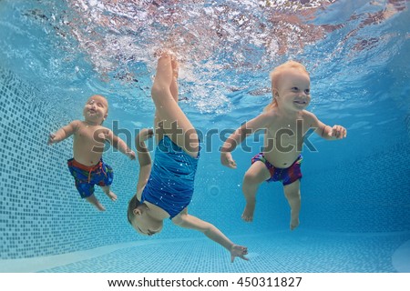 Funny photo of active babies swim and dive with fun - jump deep down underwater with splashes in swimming pool. Family lifestyle and summer children water sports activity and lessons with parents.