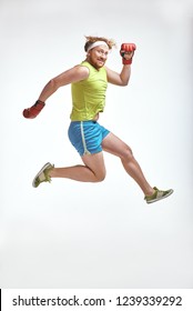 Funny picture of red haired, bearded, plump man on white background. Man wearing sportswear and red boxing gloves