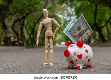 A funny piggy bank and 100 American dollars stands on the asphalt against the background of the city boulevard