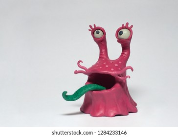 Funny pink monster bacterium with a long tongue. Plasticine character on a white background