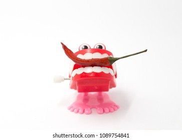A funny plastic toy bitting a spicy red chilly 