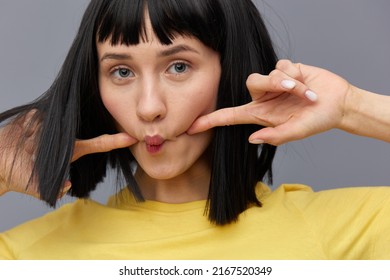 A Funny, Playful, Emotional Woman Makes A Funny Face By Pursing Her Lips And Holding Her Fingers On Her Cheeks. Horizontal Photo 