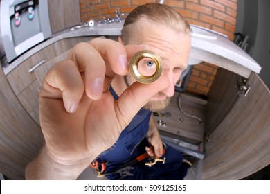 Funny plumber repairing sink in kitchen