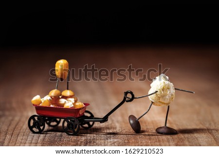funny popcorn figure is moving a handcart with a corn figure, concepts like Father's Day or playing with the kids