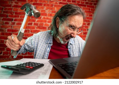 Funny Portrait Of Angry Crazy Man Attacking Laptop With Hammer While Tax Prep To Balance Budget Getting Debt Deficit Finding Mistake In Calculations.