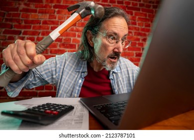 Funny Portrait Of Angry Crazy Man Attacking Laptop With Hammer While Tax Prep To Balance Budget Getting Debt Deficit Finding Mistake In Calculations.