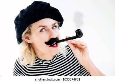 Funny Portrait Of Blond Woman As French Man With Beret, Mustache And Pipe