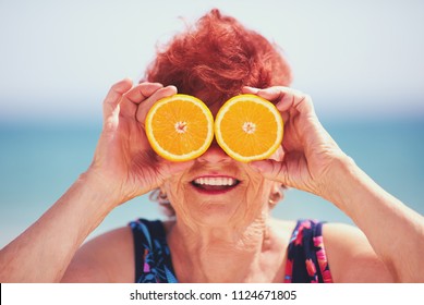 Funny Portrait Of Happy Mature Woman, Grandma Having Fun With Orange Eyes On Summer Vacation. Active Lifestyle