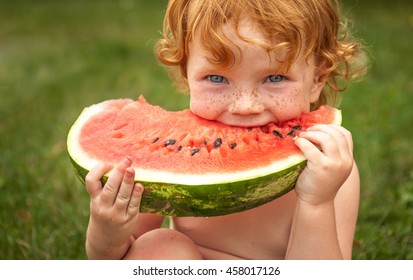 Funny Portrait Of An Incredibly Beautiful Red-haired Little Girl Eating Watermelon, Healthy Fruit Snack, Adorable Toddler Child With Curly Hair Playing In A Sunny Garden On A Hot Summer Day. Portrait