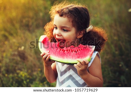 Funny portrait of an incredibly beautiful Red-haired little girl eating watermelon, healthy fruit snack, adorable toddler child with curly hair