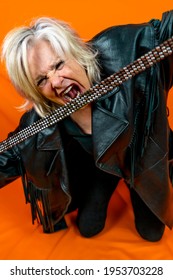 Funny Portrait Of Mature Woman. Beautiful Lady Have Fun As A Rock Star Dressed In Leather. Mature Woman On Colored Backgrounds