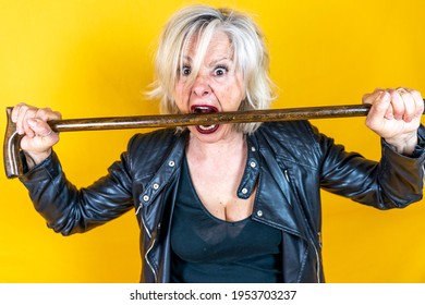 Funny Portrait Of Mature Woman. Beautiful Lady Have Fun As A Rock Star Dressed In Leather And A Walking Stick 
. Mature Woman On Colored Backgrounds