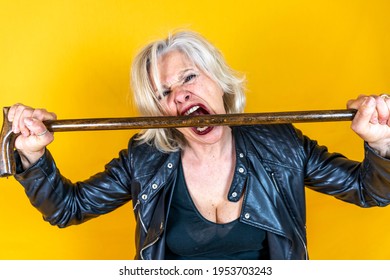 Funny Portrait Of Mature Woman. Beautiful Lady Have Fun As A Rock Star Dressed In Leather And A Walking Stick 
. Mature Woman On Colored Backgrounds