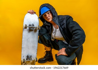 Funny Portrait Of Mature Woman. Lady Having Fun With Skate Dressed As Rapper. Mature Woman On Colored Backgrounds 